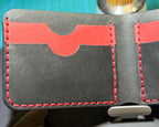 Black leather wallet card-slot detail with red hand stitching