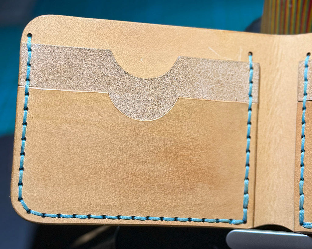 Natural leather wallet card-slot detail with baby blue hand stitching