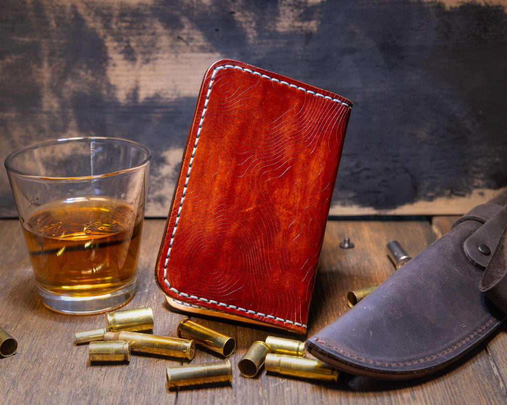 Angled exterior of the Bourbon vertical wallet showing the hand-dyed color variation and topographic engraving.
