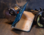 Side view of the Deep Blue Water vertical wallet showing its fold, leather edges and interior maker's mark.