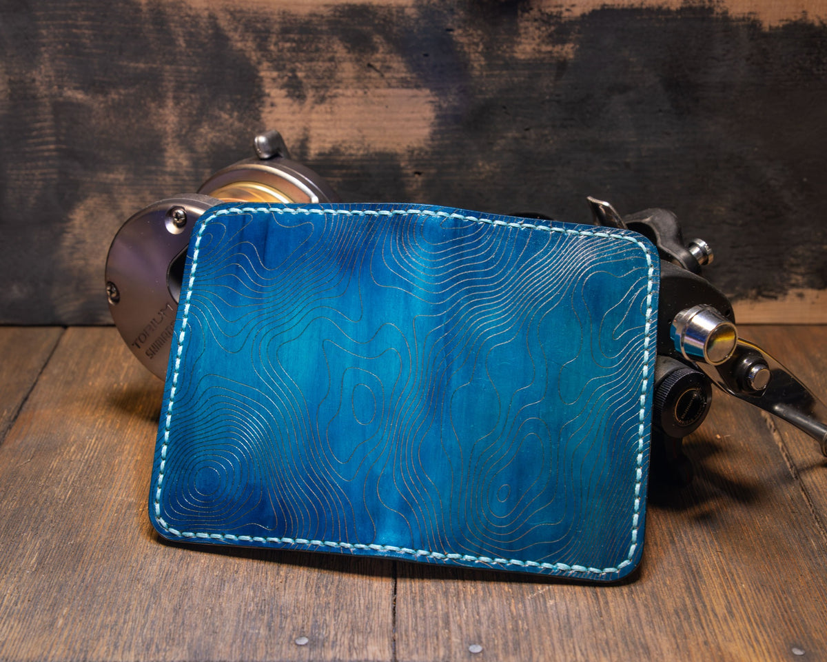 Deep Blue Water wallet opened flat to show the continuous blue topographic leather exterior and contrast stitching.
